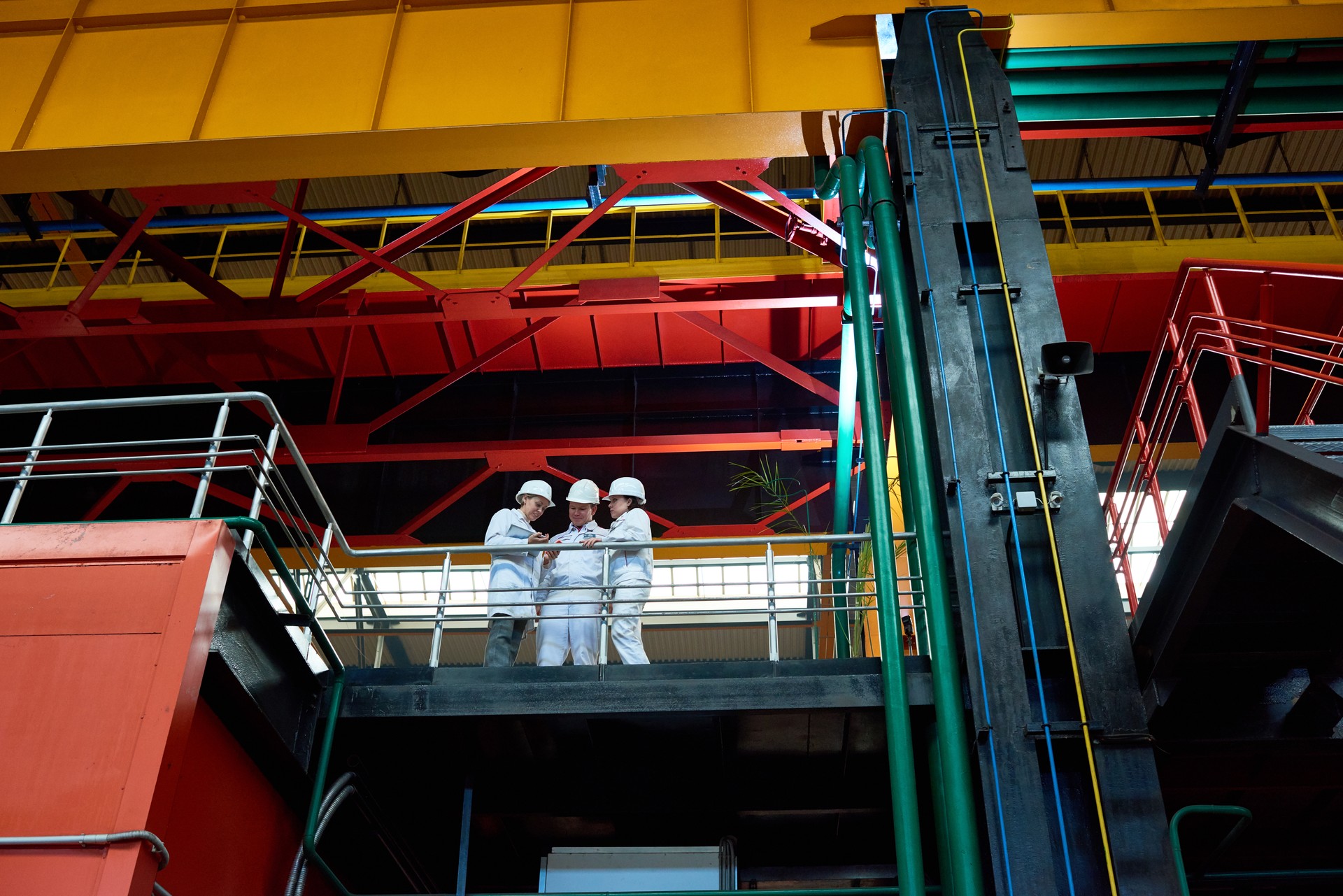 Pensive engineers standing on factory bridge and discussing production